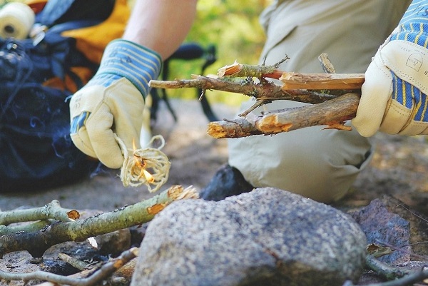 Hands in gloves with kindling and a natural fire starter