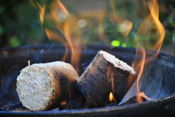 Briquette fire logs burning in a fire bowl - firewood alternative fuel