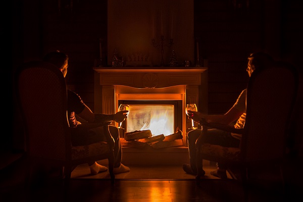 Two people sitting in front of a fireplace