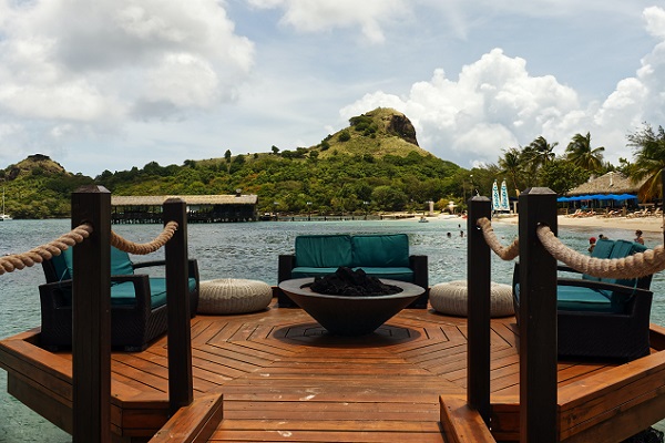 Gas fire pit on timber decking with sofas and a view onto water and mountains